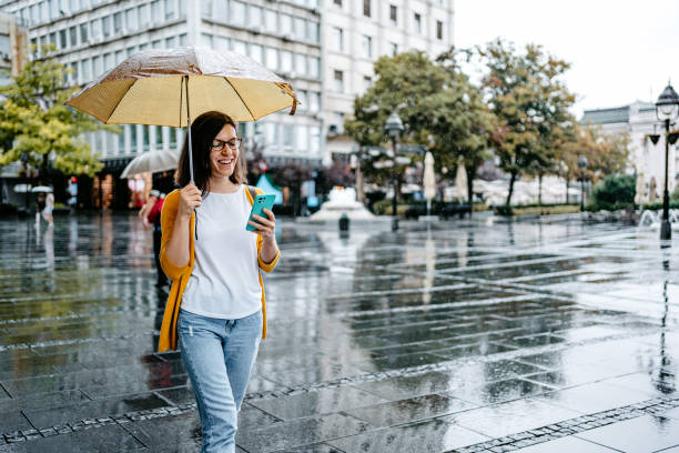 istock Young Woman Using Phone Outdoors On A Rainy Day 1424219963