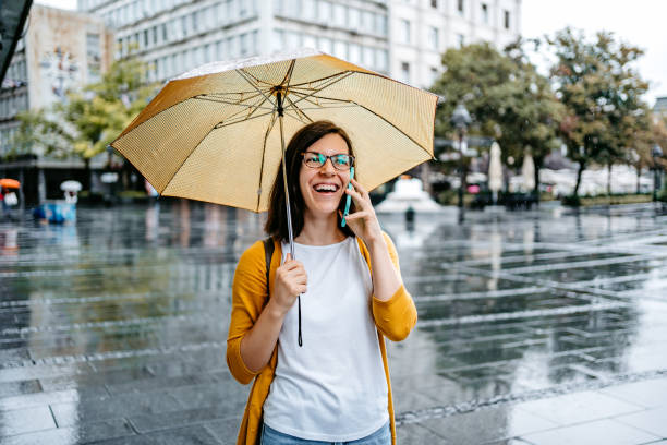 istock Young Woman Talking On The Phone Outdoors On A Rainy Day 1424219979
