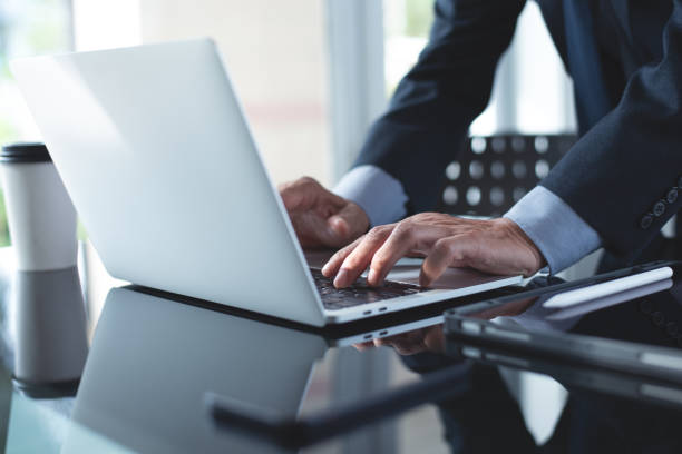 istock Businessman online working with laptop computer, surfing the internet, searching information with digital tablet on office  table 1424220037