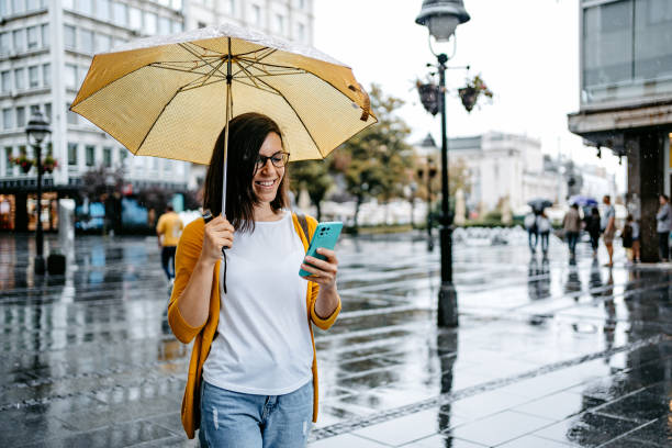 istock Young Woman Using Phone Outdoors On A Rainy Day 1424220055