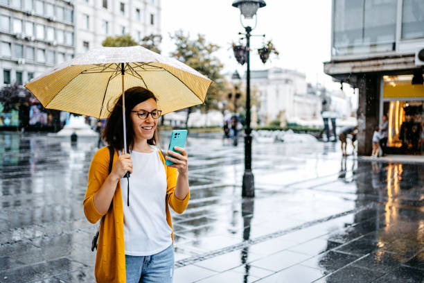 istock Young Woman Using Phone Outdoors On A Rainy Day 1424220066