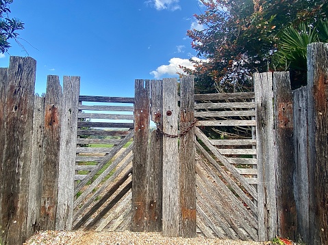 Horizontal landscape of rustic timber fence in rural country property under blue spring sky Australia