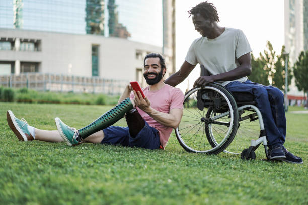 istock Multiracial friends with disability having fun using mobile phone at park city - Focus on left man hand 1424221500