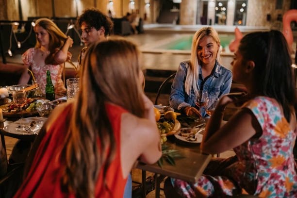 istock Four women and one man enjoy dinner not far from the pool 1424235036