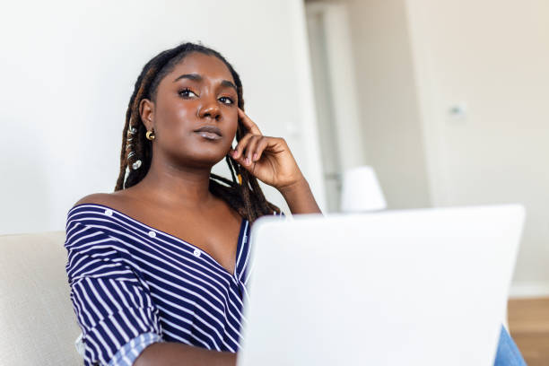 istock Nice beautiful African woman work at the notebook on the sofa at home - check on oline shops for cyber monday sales - technology woman concept for alternative office freelance 1424241721