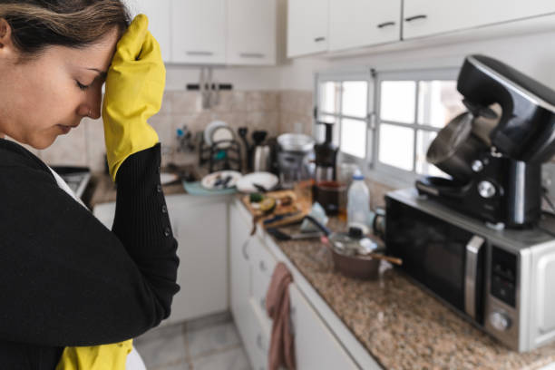 Woman wearing cleaning gloves worried about her dirty kitchen. stock photo