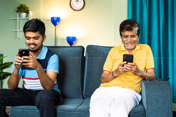 istock Focus on father, father and son busy using smartphone while sitting on sofa in distance at home - concept of Mobile phone addiction, digital technology and family. 1424245944