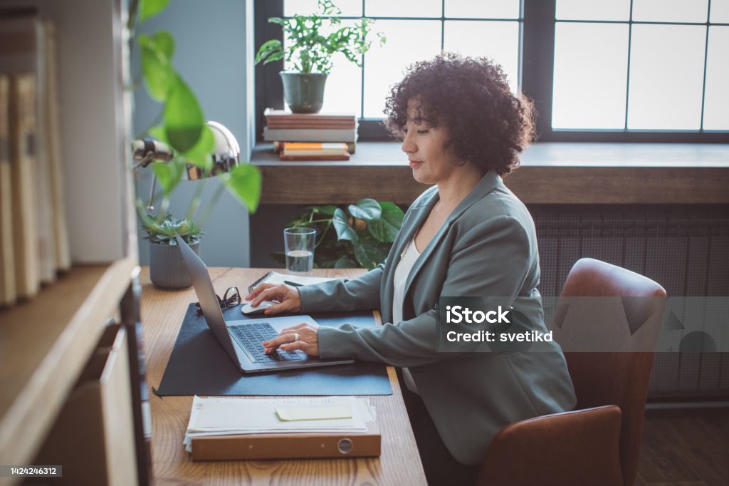Book publisher at office Mature woman at her office. She is book publisher and reading book script. 50-54 Years Stock Photo