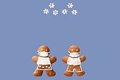 PF 2023 inscribed in snowflakes falling on gingerbread couple with protective face masks. Original New Year greeting card in coronavirus (COVID-19) time
