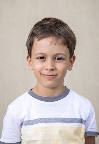 Smiling teenage boy with school bag in front of school