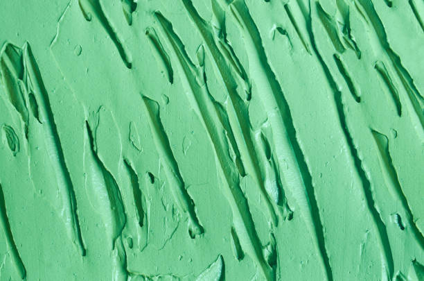 istock Green cosmetic clay (cucumber facial mask, avocado face cream, green tea matcha body wrap) texture close up, selective focus. Abstract background with brush strokes. 1424256566