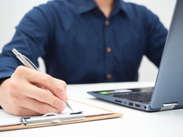 istock Close up hand of man writing on document board on the table with laptop,Work from home concept 1424256888
