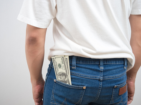 Close up back of man money dollar in trousers jean pocket portrait white background