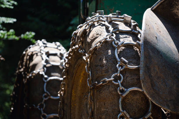 Traction chains on the big wheel of a forest log truck tree harvester working woodcutter.