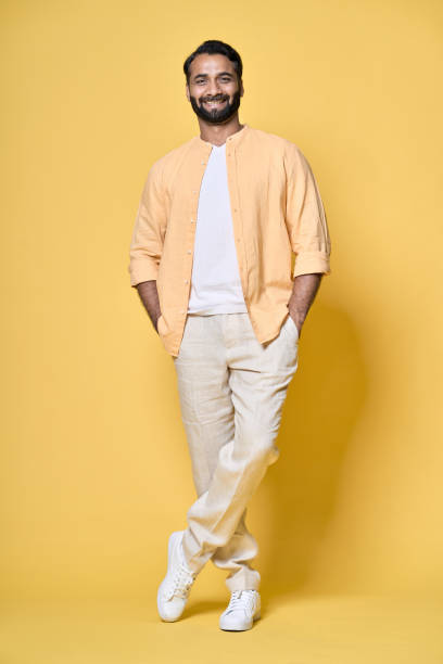 istock Smiling confident indian man standing isolated on yellow. Vertical full length 1424261799