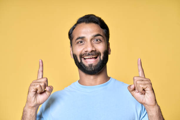 istock Excited indian man pointing up advertising ecommerce offer isolated on yellow. 1424261802