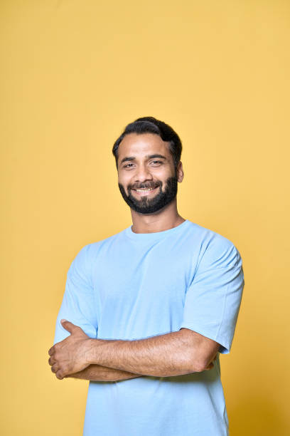 istock Smiling confident indian man standing isolated on yellow background, vertical. 1424262033