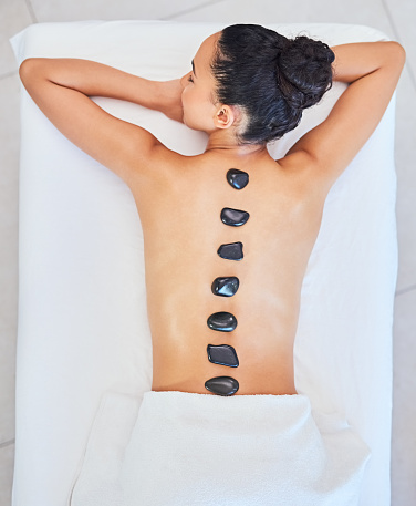 Zen relax woman getting back massage therapy with hot stone. Attractive beautiful girl lying on massage table, getting luxury physiotherapy from masseuse for skin and body care in spa beauty salon