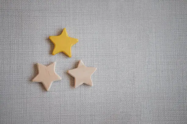 Photo of Wooden three star shape and one star painted yellow. The best excellent business services.