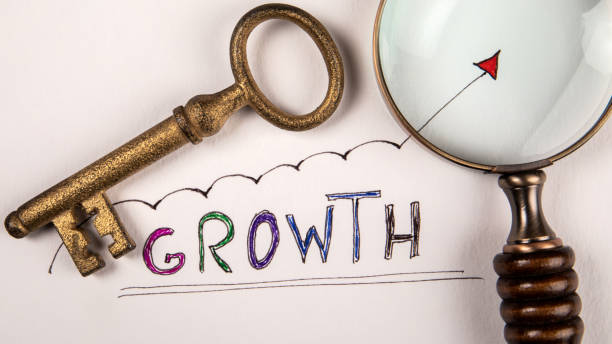 istock Growth concept. Magnifying glass and door key on white background 1424267121