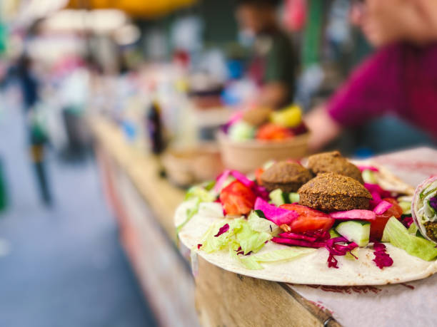 Fresh falafel and salad on display at vegan vegetarian stall at food market Close up selective focus color image depicting a food stall at a street food market in London, UK, selling fresh vegetarian and vegan take away food. The food on display includes fresh salad and falafel. Focus on foreground with background blurred out of focus. food festival stock pictures, royalty-free photos & images