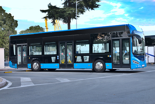Modern blue bus at a bus station.