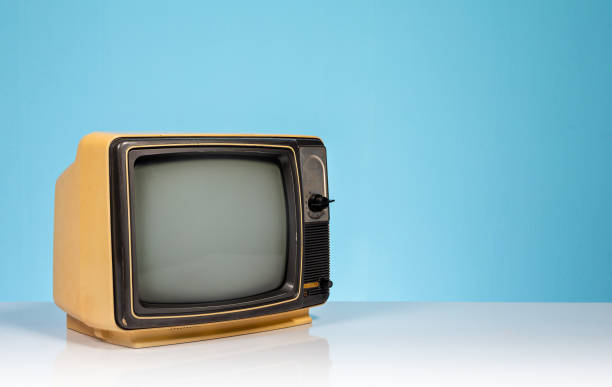 istock Old retro yellow TV receiver set on white table on blue background 1424274317