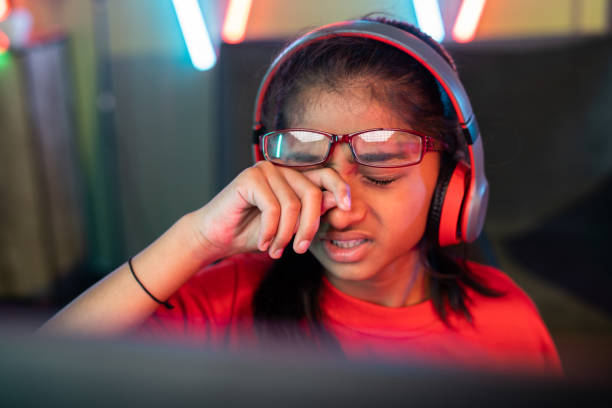 foco na mão, menina cansada e exausta esfregando os olhos removendo óculos enquanto joga videogame online em casa - conceito de vício em tecnologia, irritação nos olhos e torneio de jogos. - indian girls audio - fotografias e filmes do acervo