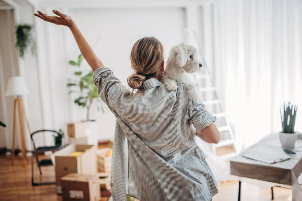 Woman with her dog in new home One woman, young woman in her new home, she is holding her pet dog. unpacking stock pictures, royalty-free photos & images