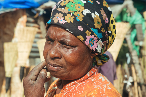 Old African woman scratching her face, stressed thinking at daily needs