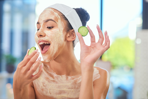 Woman doing facial mask with cucumber at home, self care for skincare and wellness of beauty skin at house. Person eating healthy fruit with spa day in apartment and doing luxury routine for therapy
