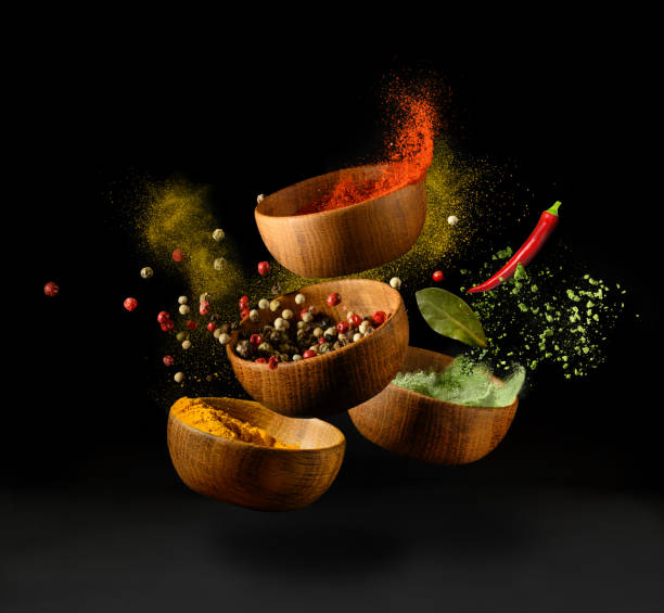 Spices and seasonings powder splash, explosion on black background Colorful spices and peppers in wooden bowls flying over black background. Spices and seasonings powder splash. Freeze motion photo. seasoning stock pictures, royalty-free photos & images