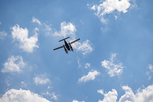Single engine seaplane against a clear blue sky with white clouds seen at the Dumbo district in Brooklyn