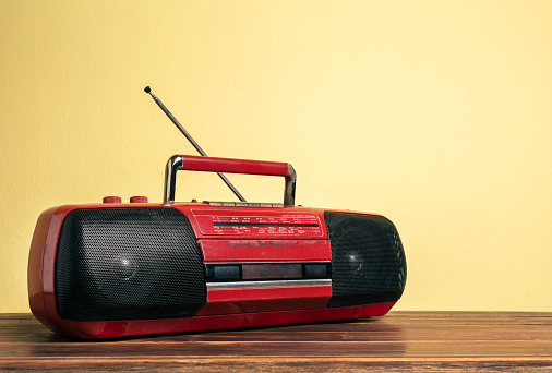 Grabadora de casete de radio portátil antigua de color rojo retro frente a una pared de hormigón amarillo. photo