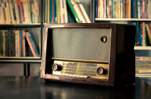 Old fashioned radio on table in the home library. Vintage filter photos