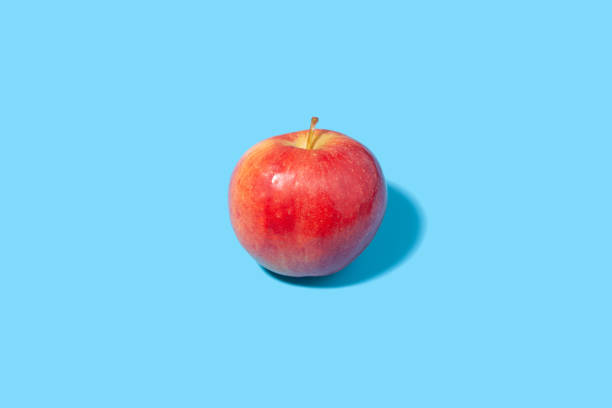 istock Big ripe red apple on a blue background - juicy summer fruit 1424299018
