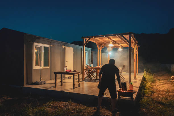 istock Mature man preparing barbecue dinner in backyard of container house. 1424303598