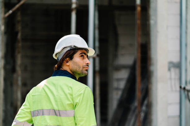 istock Construction worker with safety helmet on head in vest looking at construction site 1424306848