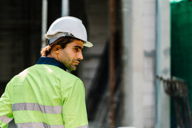 istock Construction worker with safety helmet on head in vest looking at construction site 1424306876