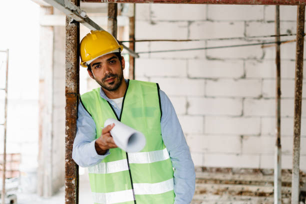 istock Construction worker with safety helmet on head and in vest  holding blueprint at construction site 1424307166