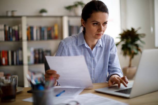 Serious mature woman paying her utility bills online stock photo