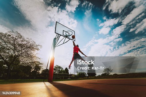 istock Street basketball player making a powerful slam dunk on the court - Athletic male training outdoor at sunset - Sport and competition concept 1424309948