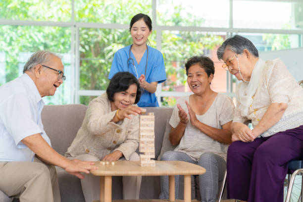 demenztherapie auf spielerische weise. gruppe älterer menschen bleibt im pflegeheim, genießt aktivität
beziehung spielen jenga oder tumbling tower wood block spiel. finger und feine fähigkeiten trainieren - concentration chess playing playful stock-fotos und bilder