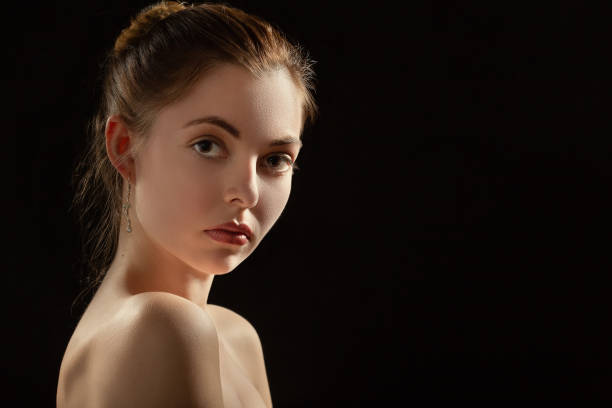 istock sad beautiful woman looking at camera on black background with copy space 1424319820