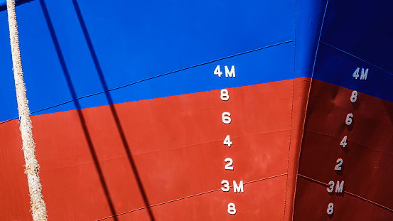 Background of draft mark numbers on blue and red steel hull surface of nautical vessel
