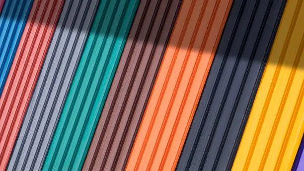 Diagonal pattern background of multi colored corrugated metal sheets for roofing on display stand with sunlight and shadow on surface