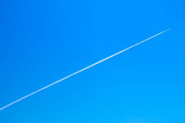 Jet airplane is flying with white contrail on blue clear sky background