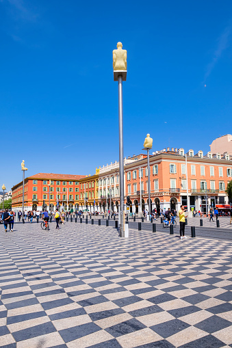 People strolling in the large Place Massena, where stands out the sculpture \