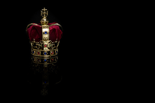 Golden crown on a black background with reflection and with copy space