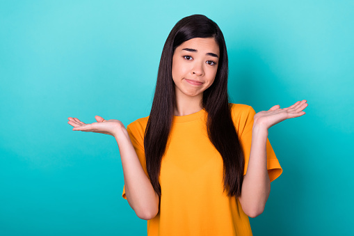 Photo of nice cute gorgeous girl with straight hairstyle dressed yellow t-shirt hands up excuse me isolated on teal color background.